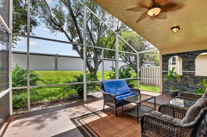 Screened patio featuring wood-finish flooring, a ceiling fan, and built-in wall niches with dark stacked stone accents