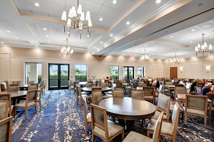 Spacious common area featuring patterned carpeting, recessed lighting, and multiple elegant chandeliers