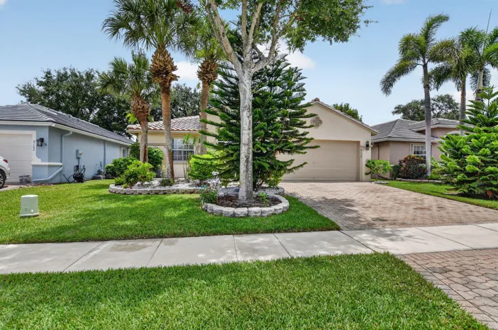 Neutral-toned residence featuring a paver driveway, an integrated garage, and a tiled roof