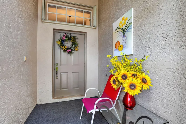Entryway featuring a paneled door with a transom window above, textured stucco walls, and a grey carpeted floor