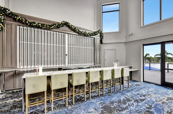 Spacious interior with high ceilings and large windows, featuring a built-in bar with seating for multiple guests