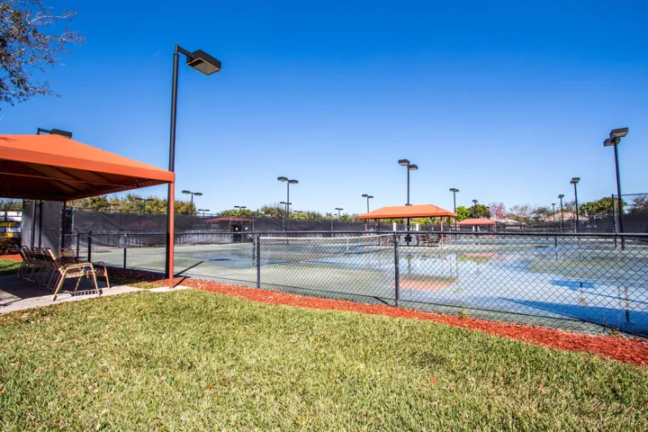 Multiple tennis courts featuring perimeter fencing and overhead lighting