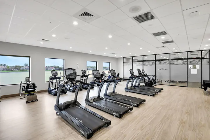 Fitness center featuring multiple cardio machines and wood-finish flooring