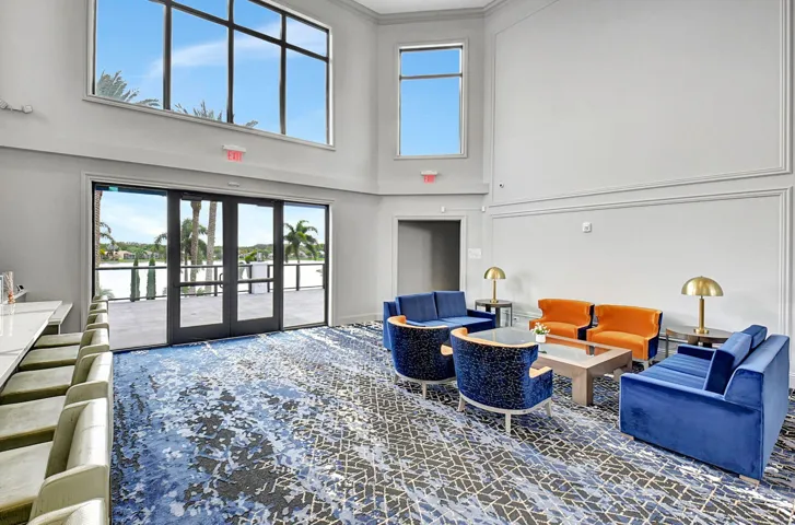 Spacious common area featuring full-height glass doors opening to an outdoor patio with water beyond