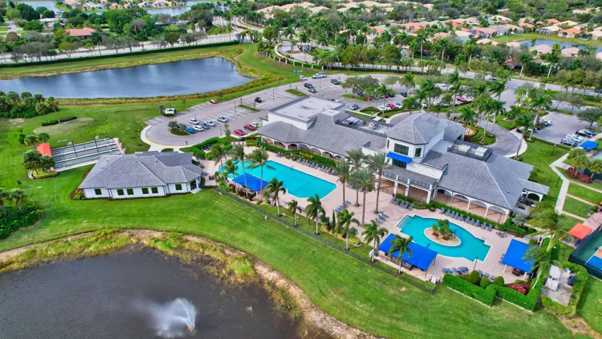 Expansive community recreation center featuring two large swimming pools, tennis courts, and a multi-level clubhouse with covered outdoor seating