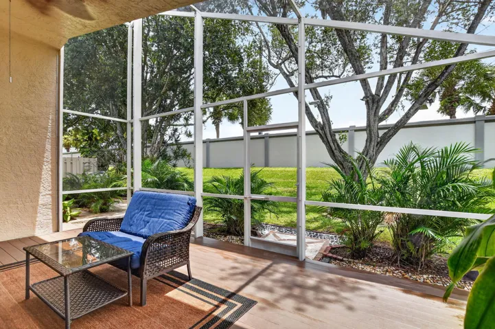 Screened patio featuring wood-finish flooring, stucco exterior wall, and a ceiling fan