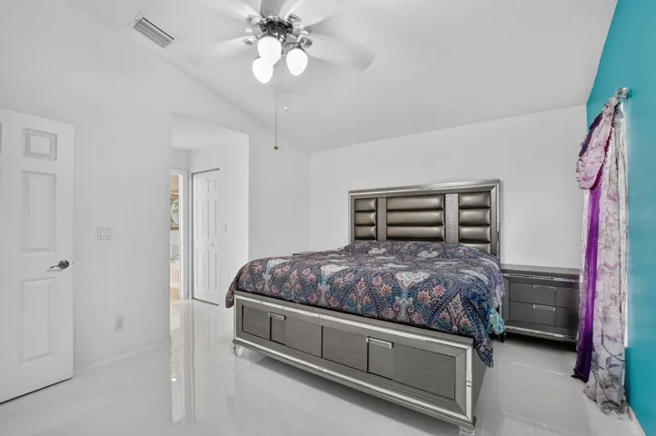 Vaulted ceiling bedroom featuring white walls, a ceiling fan, and white-finish tile flooring