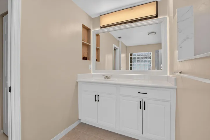 White vanity with dual cabinet storage and a single sink, featuring a polished white countertop