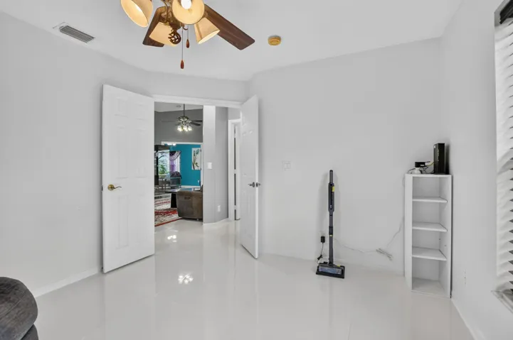 Bright interior room featuring light tile flooring and a ceiling fan with integrated lighting