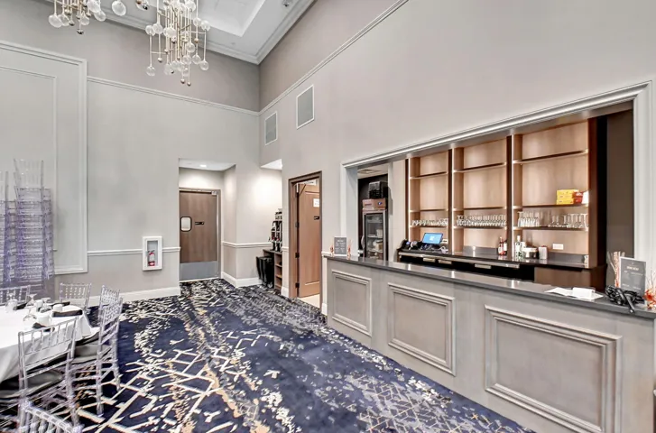 Elegant bar area featuring a paneled bar front, dark countertops, and open shelving