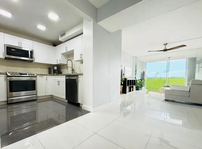 Modern kitchen featuring white cabinetry, stainless steel appliances, granite countertops, and a tile backsplash