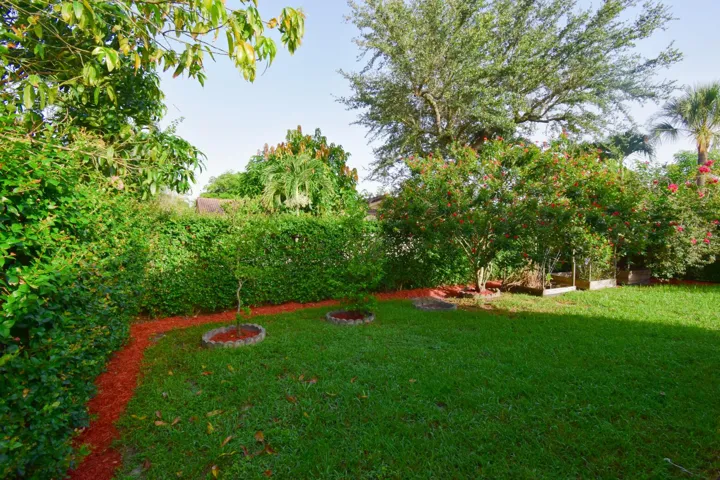Fenced backyard, privacy hedges, and flowering plants.