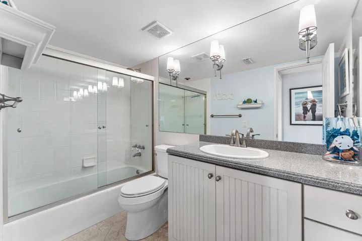 Full-length mirror extending above a vanity with a white oval sink, brushed nickel faucet, and a speckled countertop
