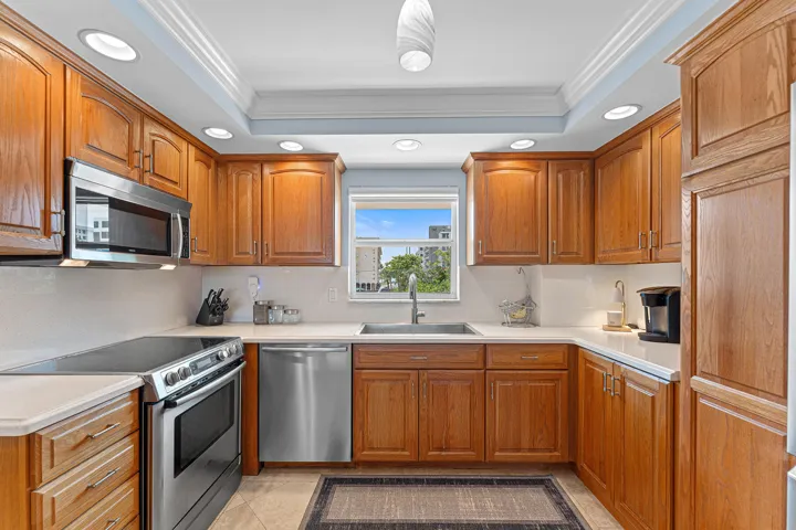 Kitchen featuring wood cabinetry, stainless steel appliances, white countertops, and recessed lighting