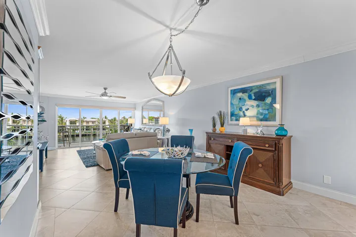 Dining area featuring a contemporary chandelier, tile flooring, crown molding, and a wood-finish buffet cabinet