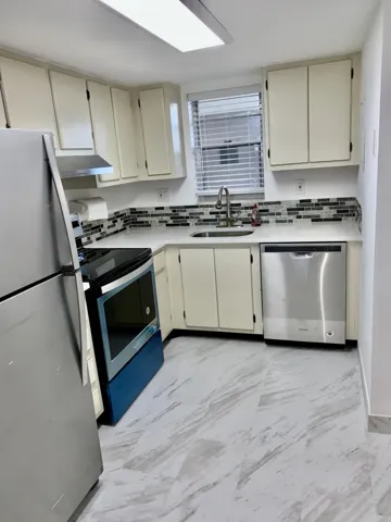 Kitchen featuring white cabinetry, a stainless steel refrigerator, and a coordinating stainless steel dishwasher