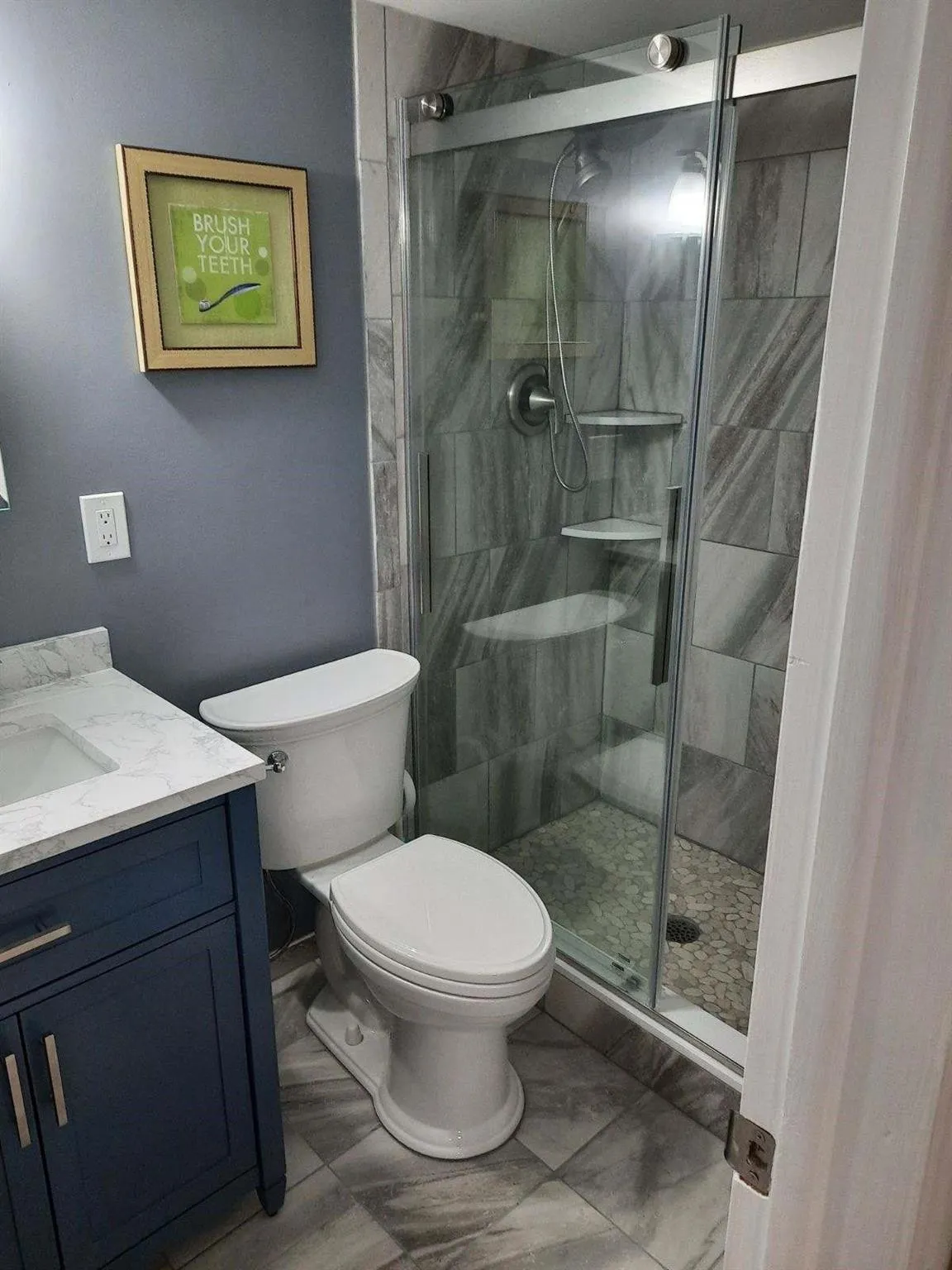Bathroom featuring a glass-enclosed shower with pebble-style flooring and tile surround
