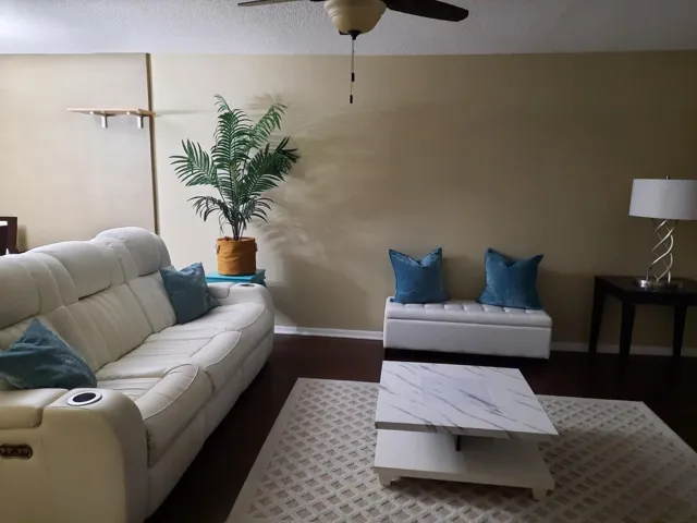 Spacious living area featuring hard-surface flooring, neutral wall tones, and a ceiling fan