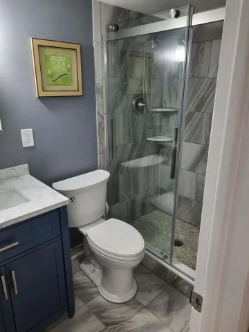 Bathroom featuring a glass-enclosed shower with pebble-style flooring and tile surround