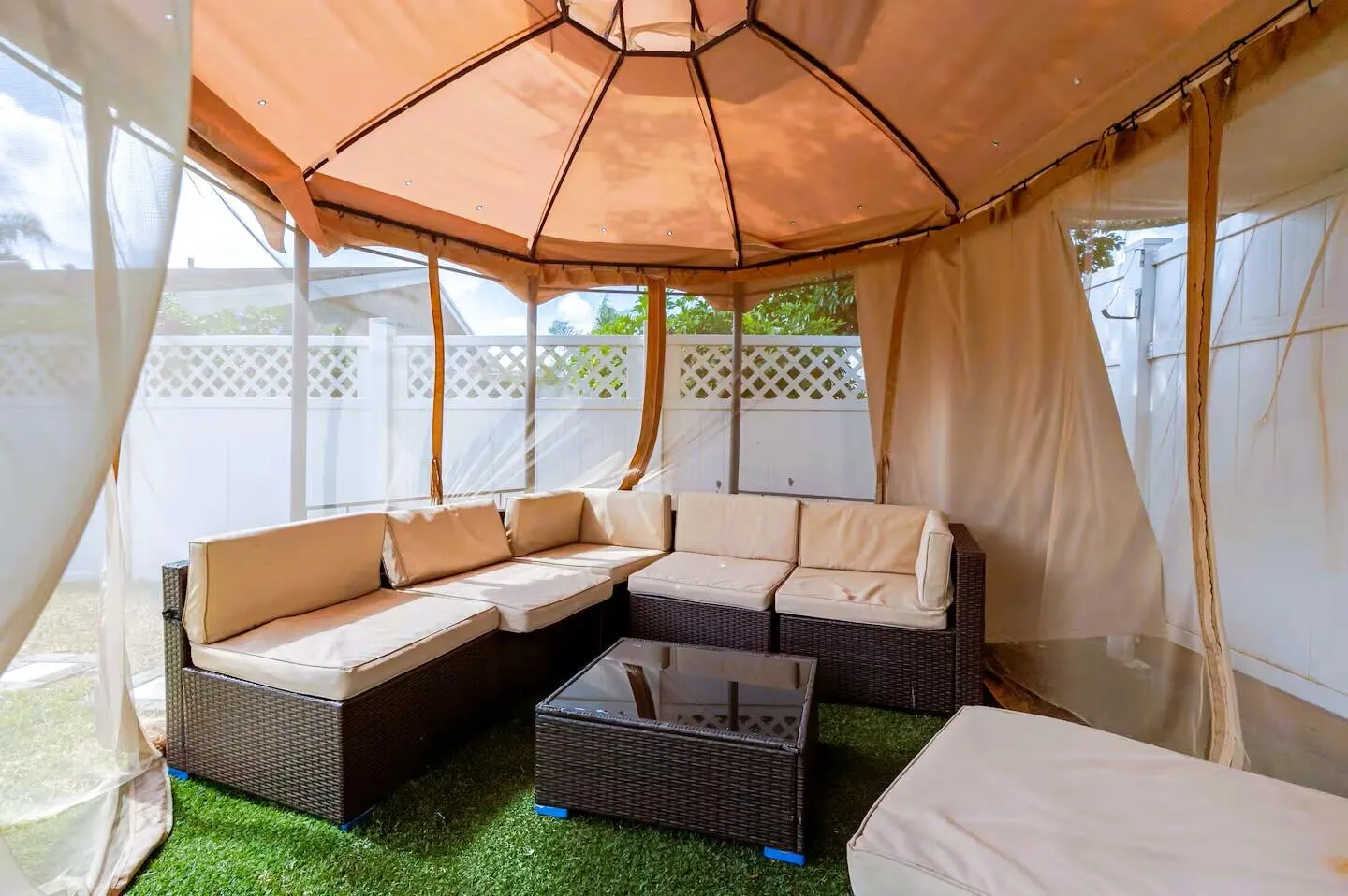 Outdoor gazebo structure with a beige fabric canopy, screen panels, and privacy curtains