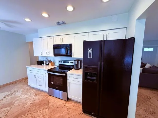 Kitchen featuring white shaker-style cabinetry, dark appliances, recessed lighting, and patterned tile flooring
