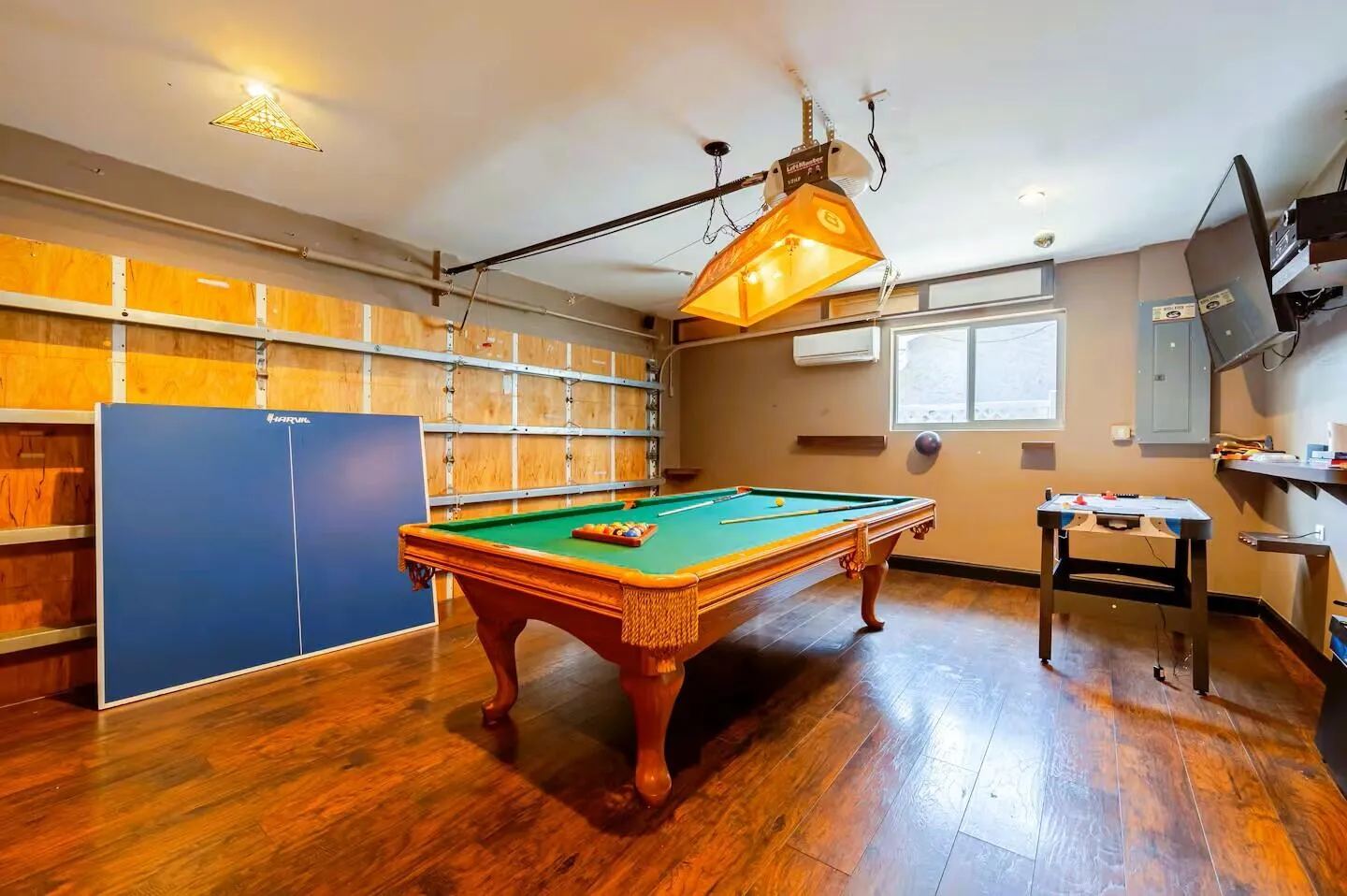 Recreation room featuring rich wood-finish flooring, a wood-framed pool table with green felt, and a suspended overhead light fixture