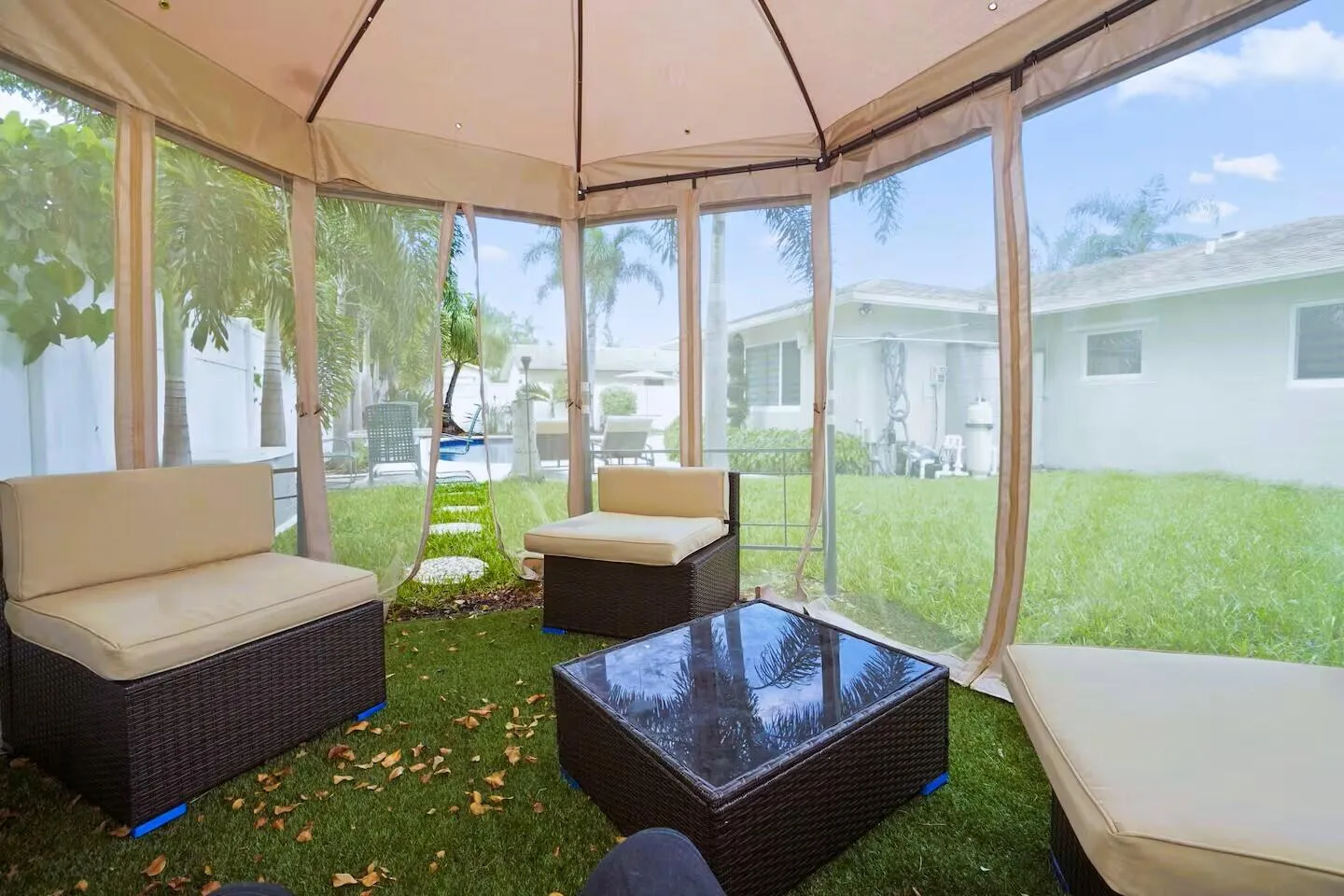 Screened outdoor enclosure featuring a fabric canopy, clear vinyl panels, and an artificial turf floor