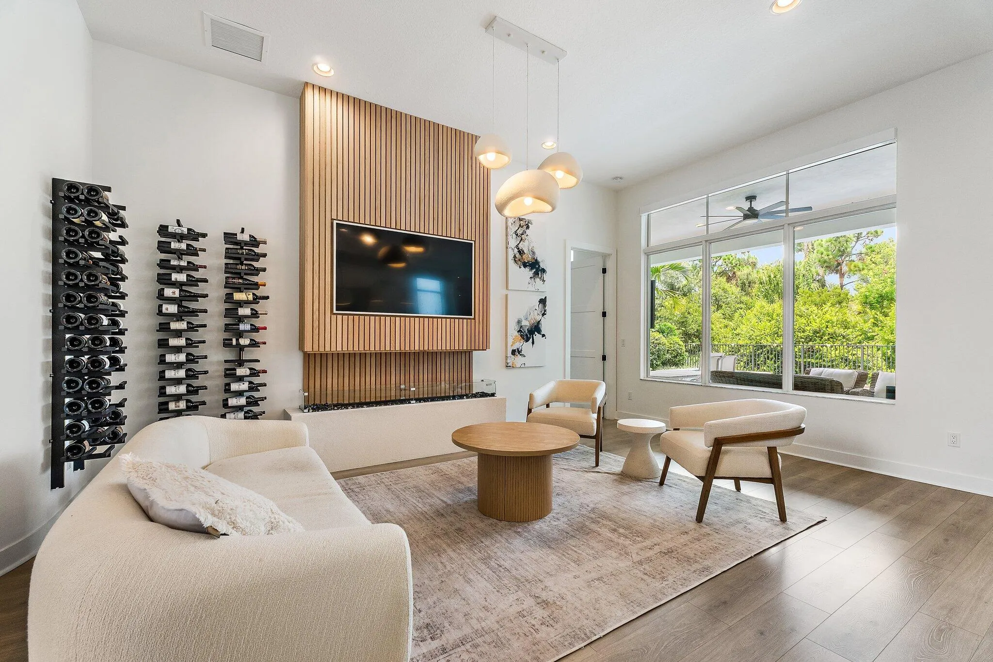 Living room with wine storage shelving, mounted TV, and large windows with garden view