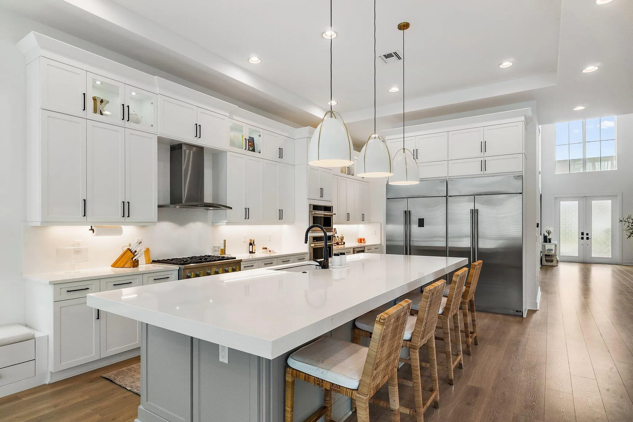 Large kitchen with oversized island, waterfall countertop, pendant lighting, and high ceiling