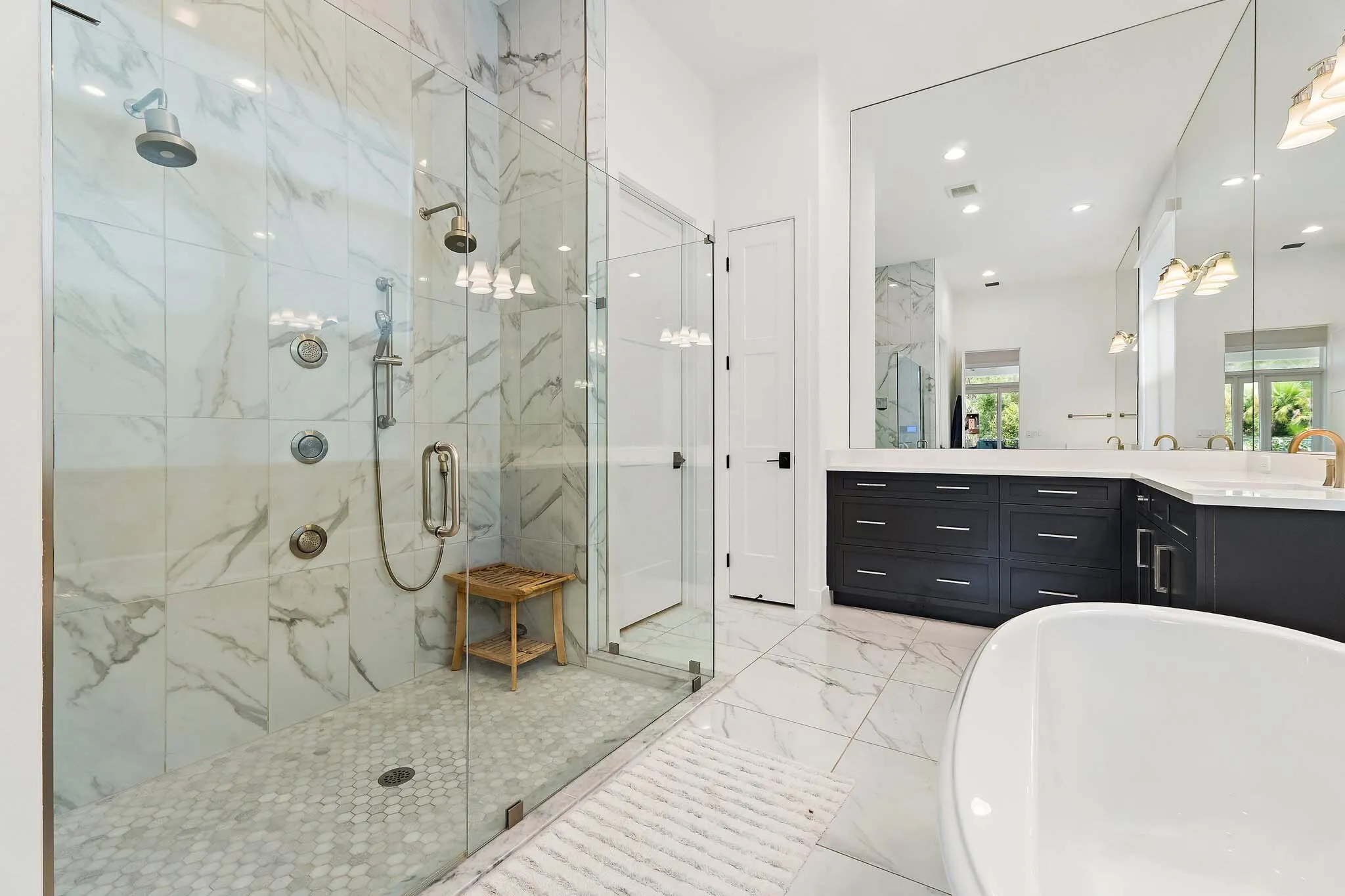 Bathroom with glass-enclosed shower, freestanding tub, and marble tile