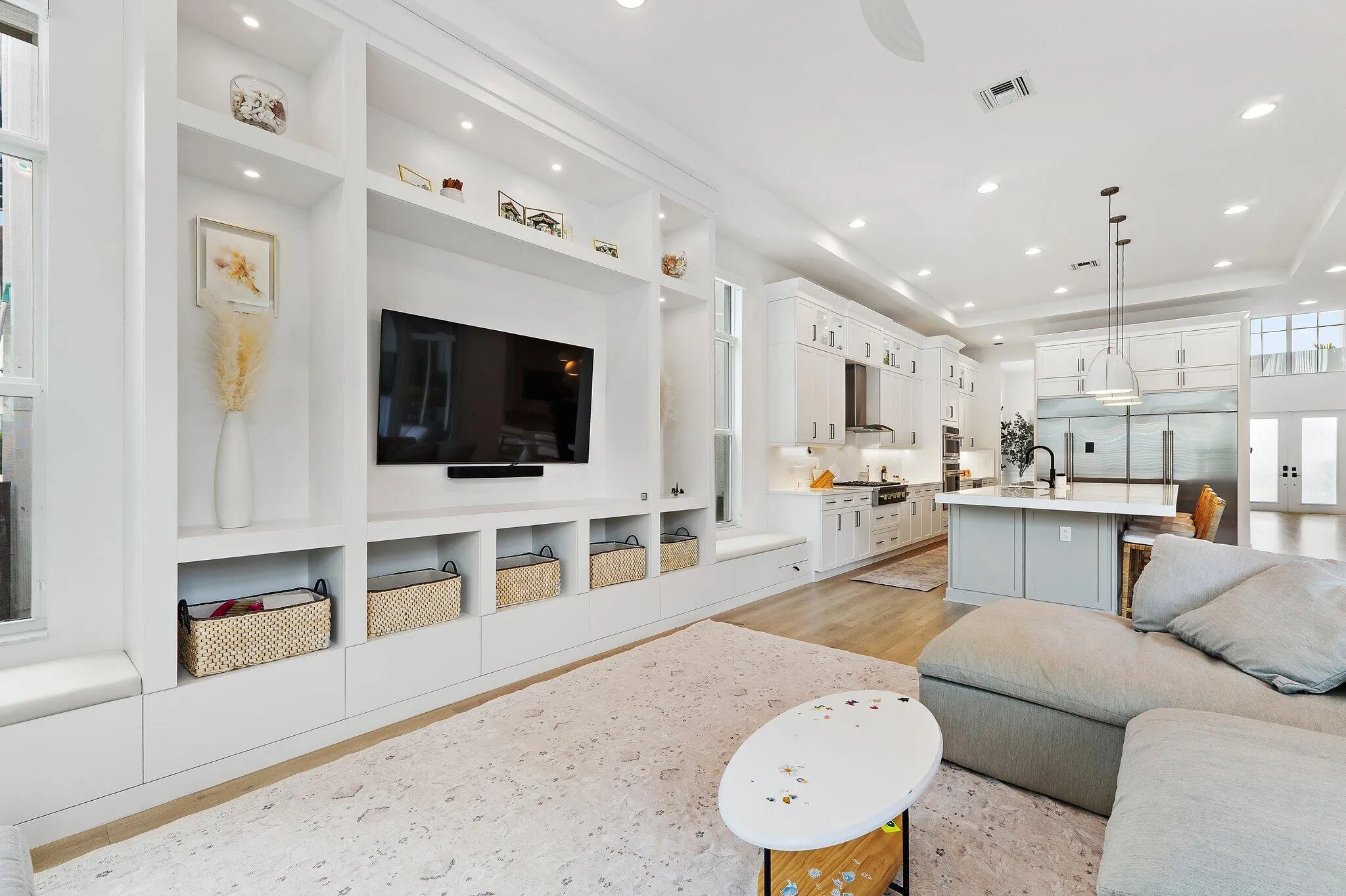 Living area with built-in shelving, mounted TV, and open view to kitchen
