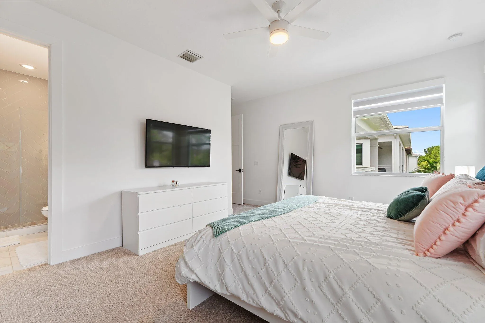 Bedroom with mounted TV, dresser, and mirror