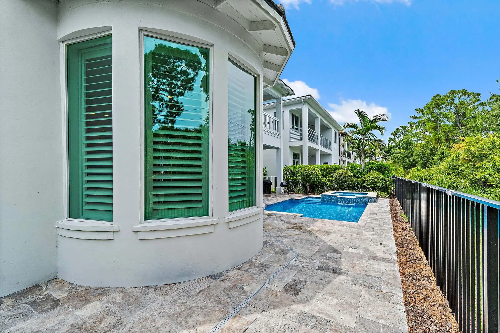 Exterior detail with plantation shutters, black fence, and pool