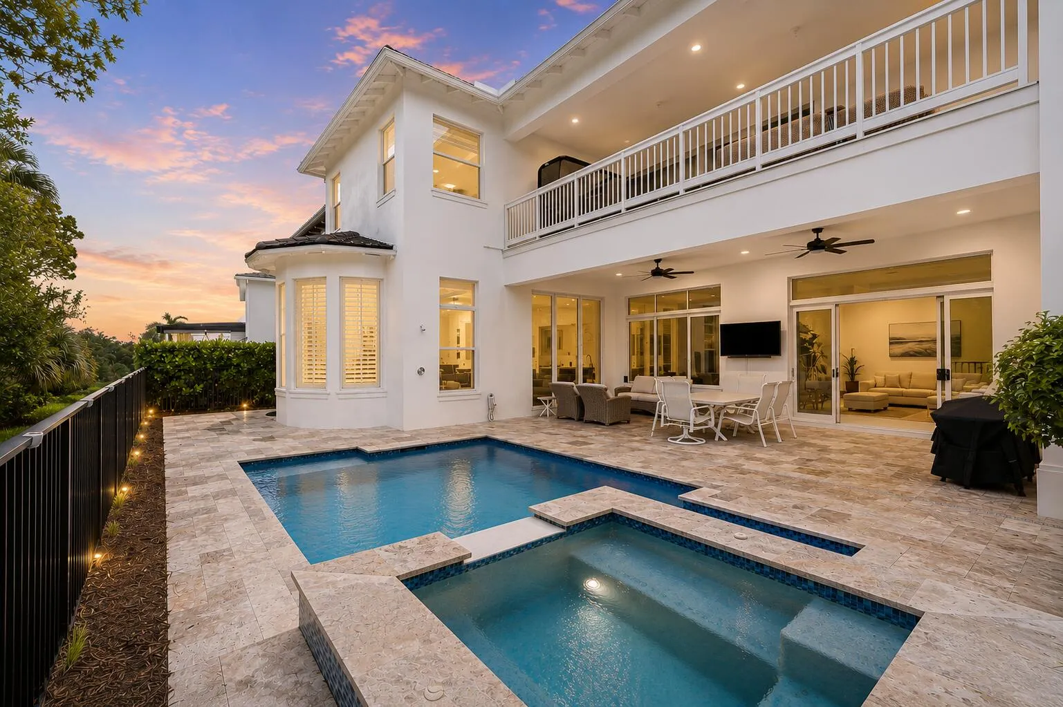 Backyard pool and spa with covered patio seating area at twilight