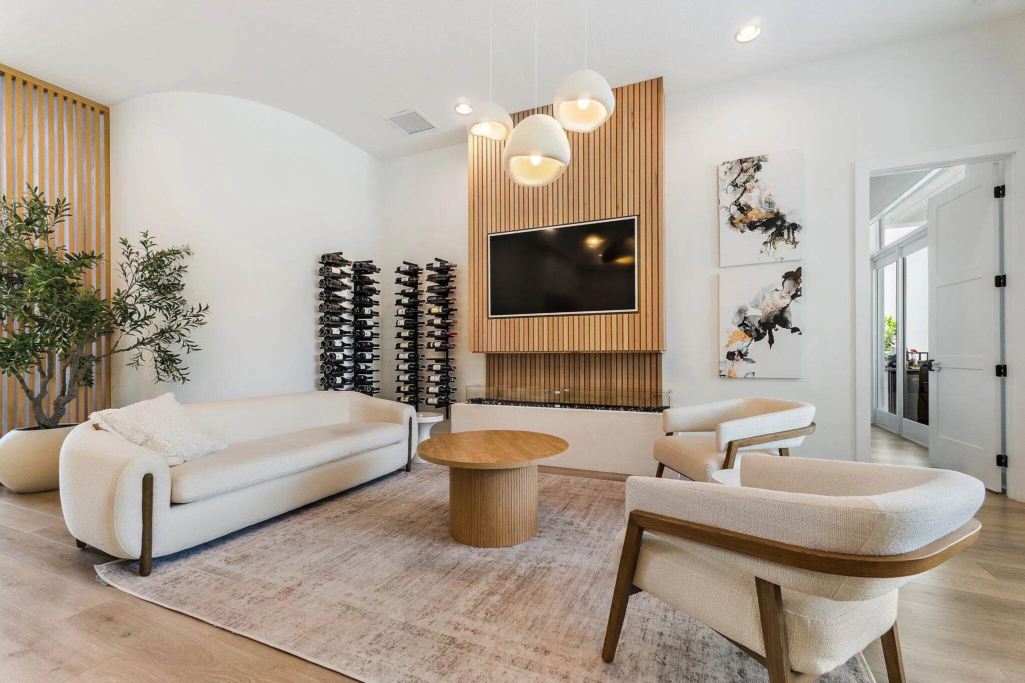 Living room with white sofa, wood accent wall, built-in wine display, and mounted TV