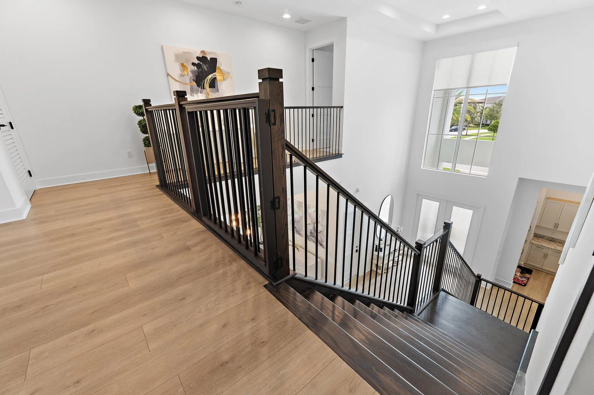 Upstairs landing with wood staircase and black iron railing