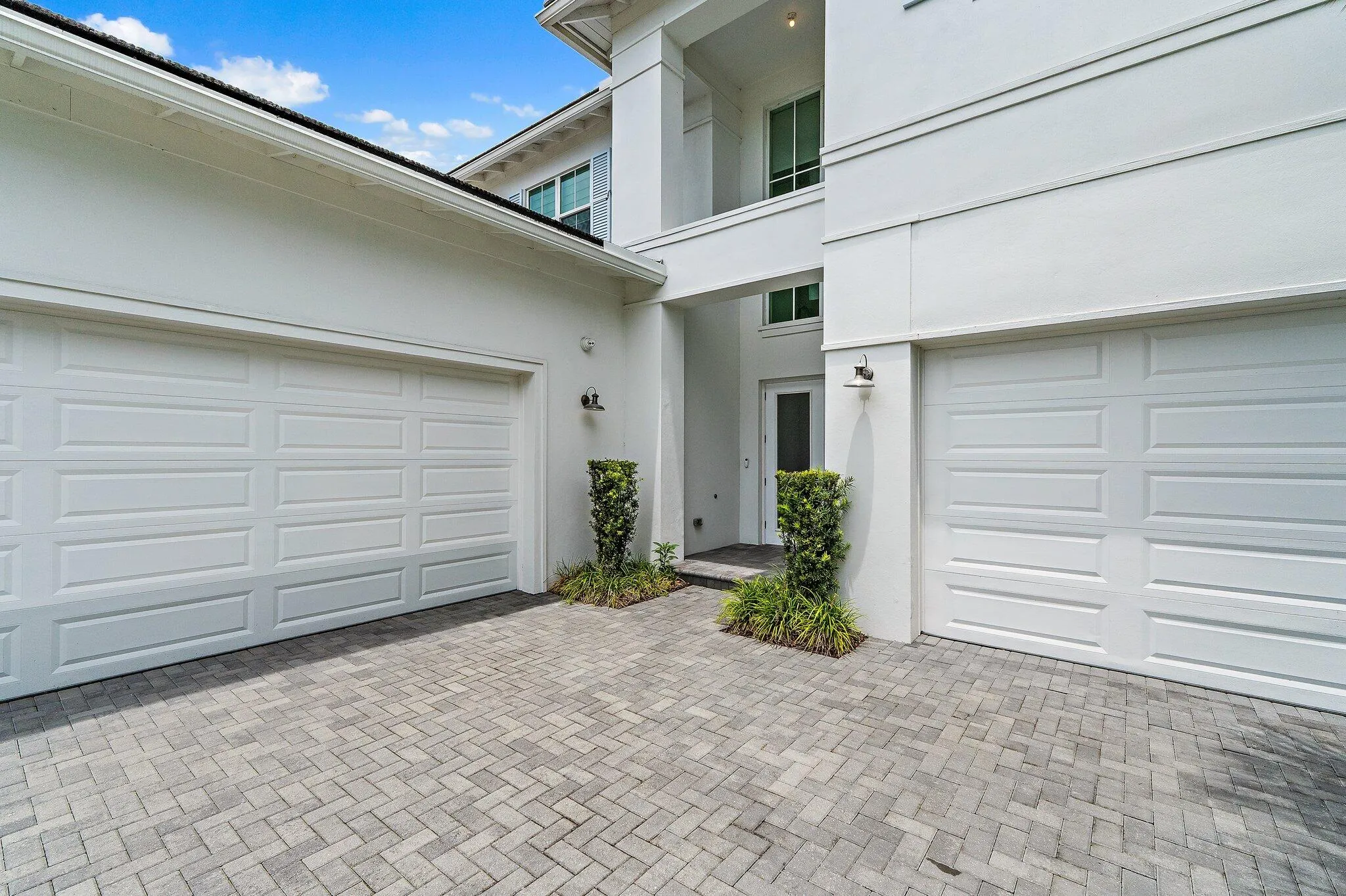 Side exterior view with two-car garage and paver driveway