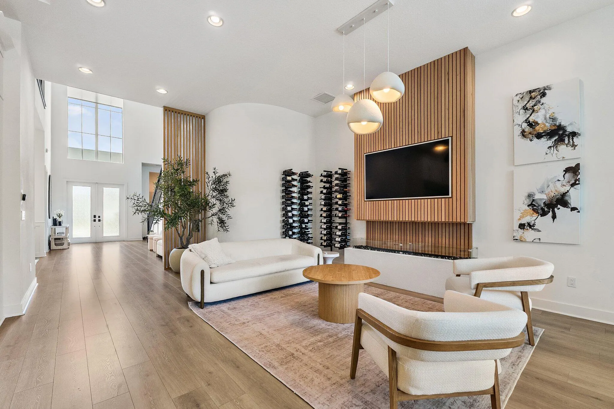 Two-story great room with wood accent wall, mounted TV, and wood flooring