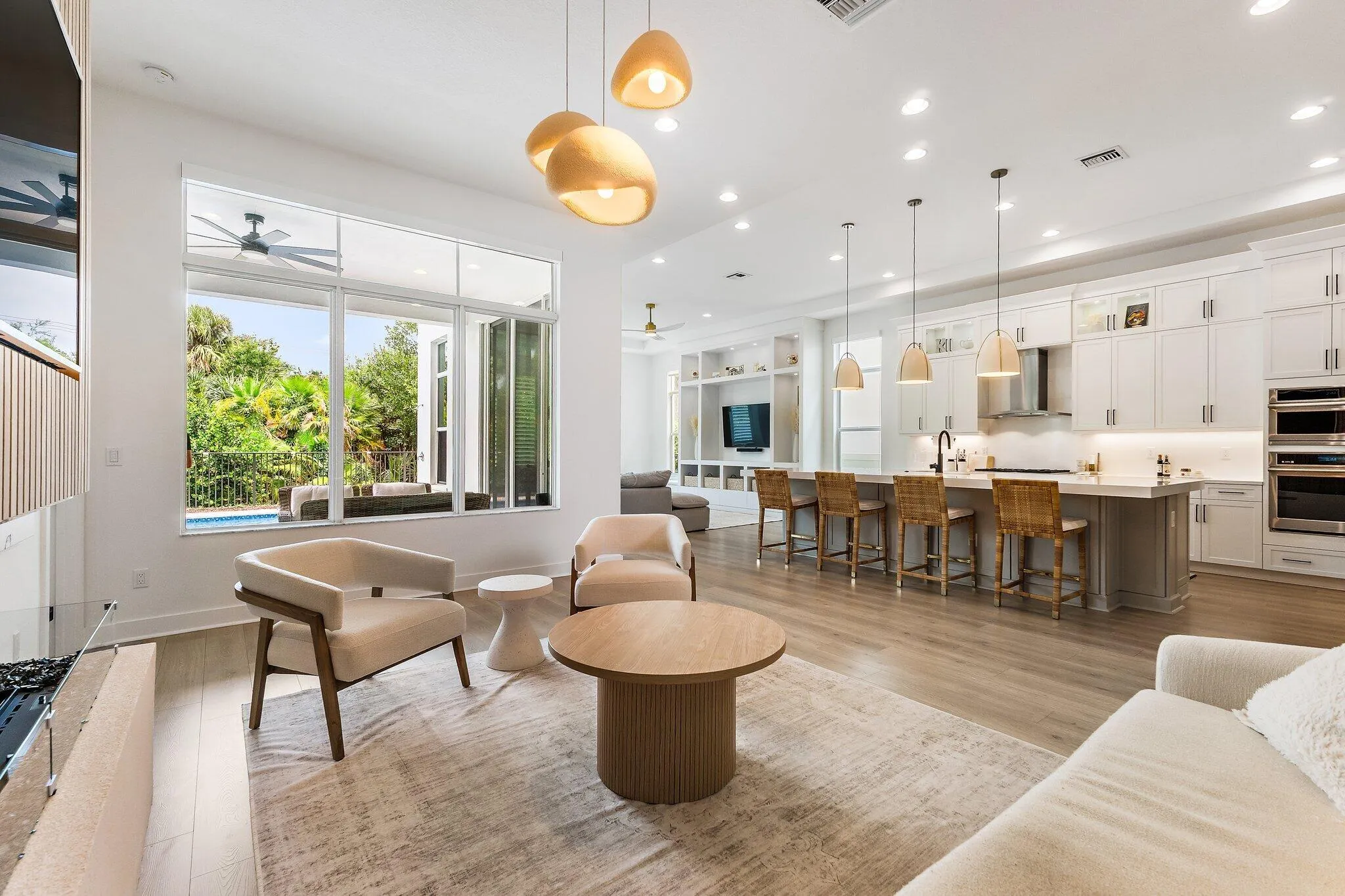 Open-concept kitchen with island, pendant lighting, and adjoining living area with glass doors to outside