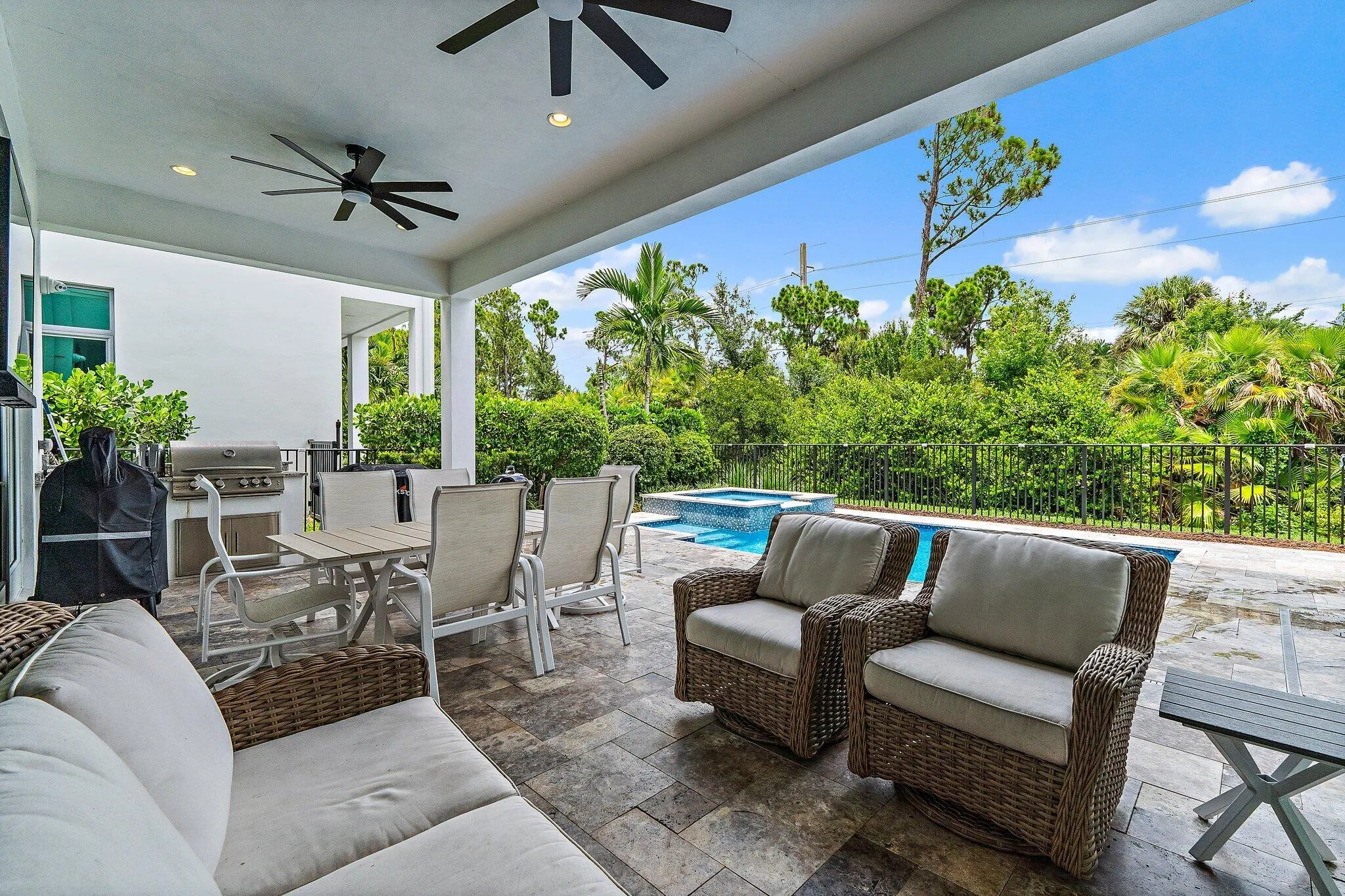 Covered patio with dining and lounge seating overlooking the pool