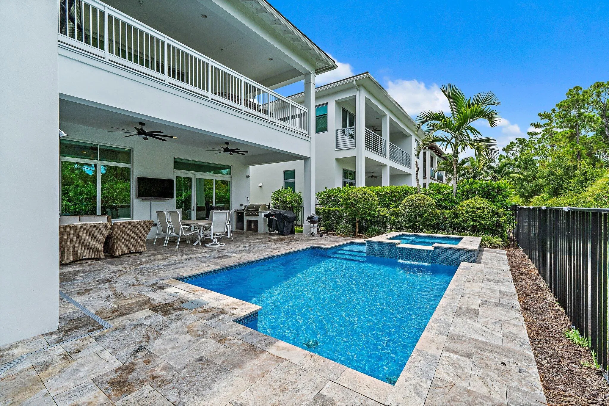 Rear exterior view with covered patio, pool, and black fencing