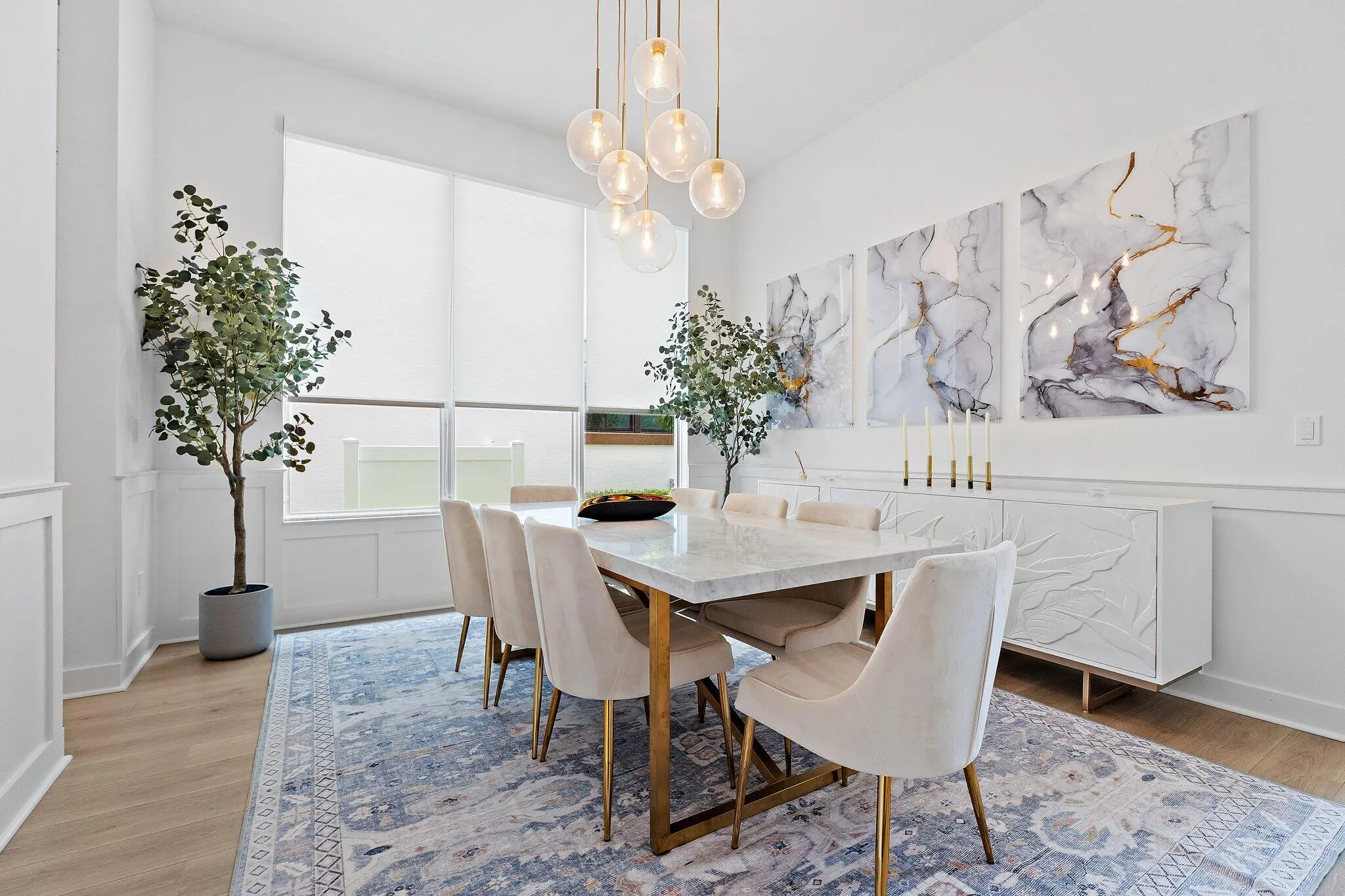 Dining room with wood table, upholstered chairs, artwork, and area rug