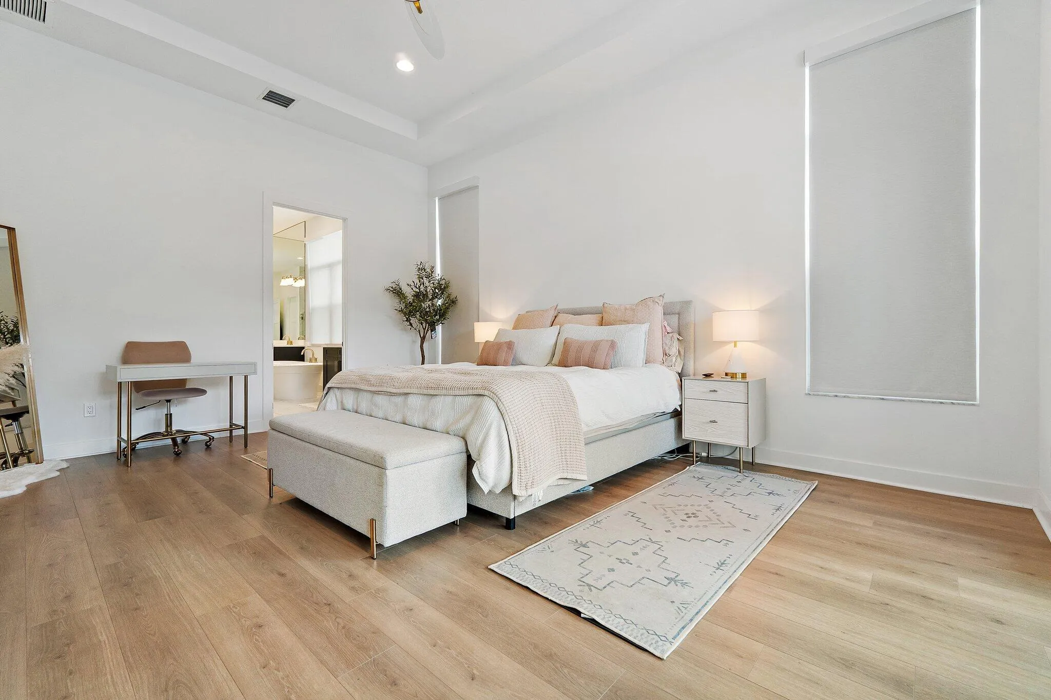 Bedroom with white bed, desk area, and wood flooring
