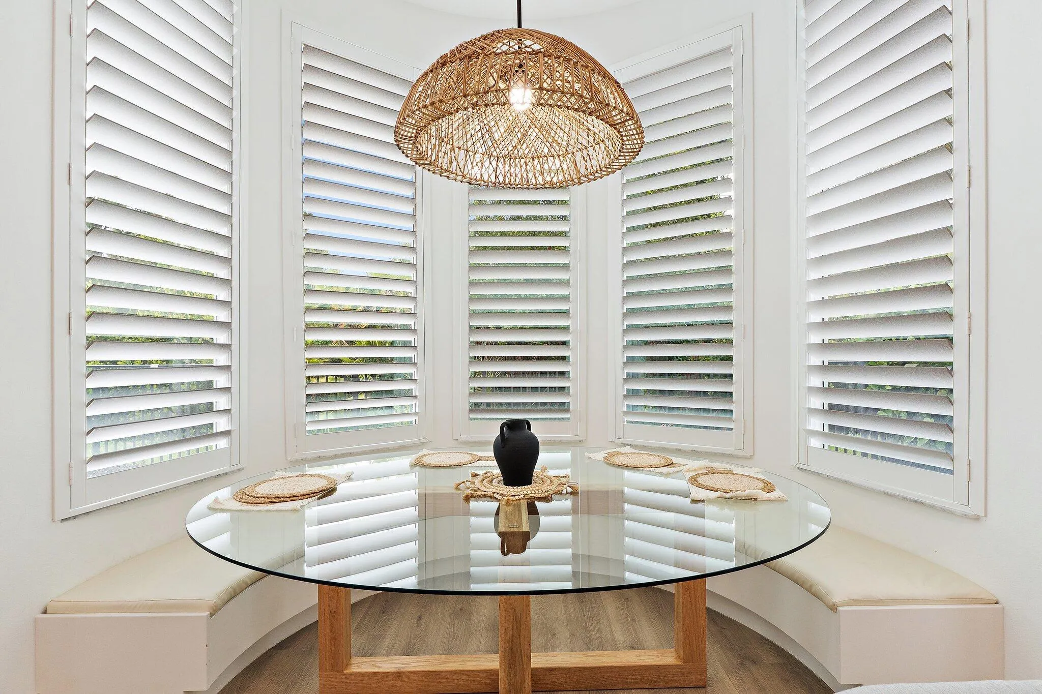 Breakfast nook with round glass table, built-in bench seating, and bay window