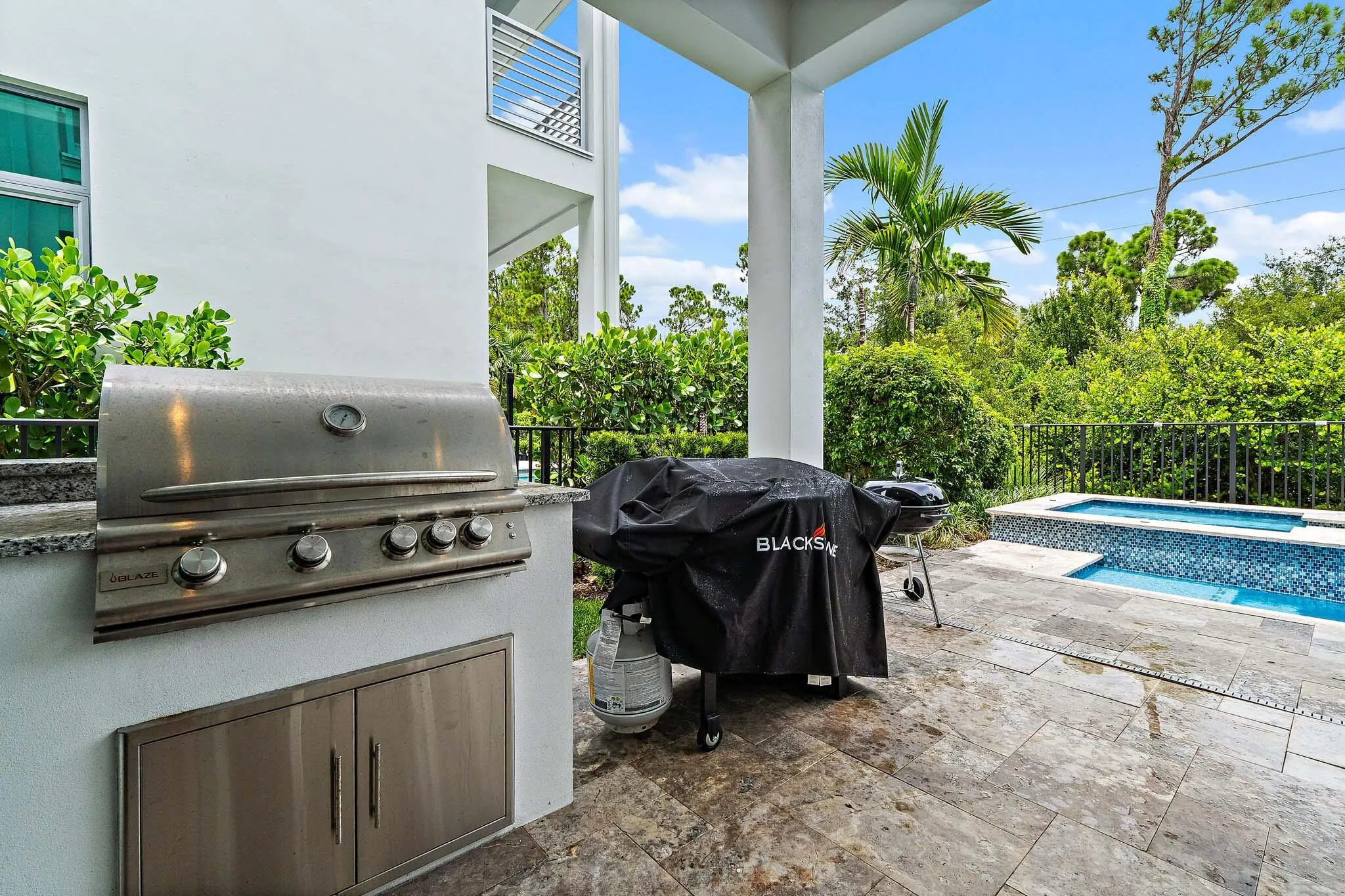 Outdoor kitchen with built-in grill and pool view