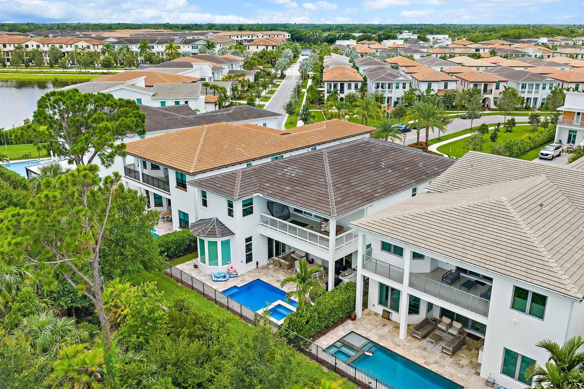 Aerial view of the home showing pool, roof, and surrounding neighborhood