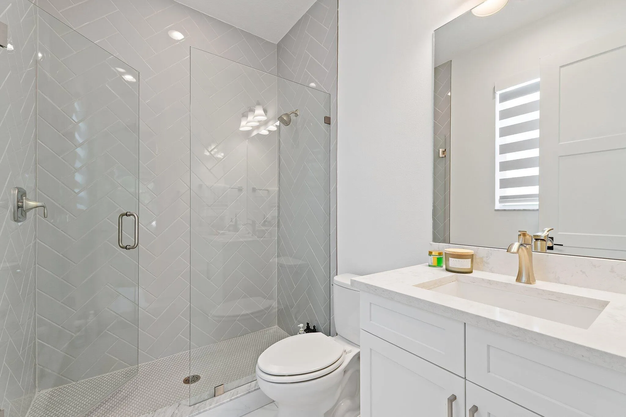 Bathroom with glass shower, white vanity, and marble tile