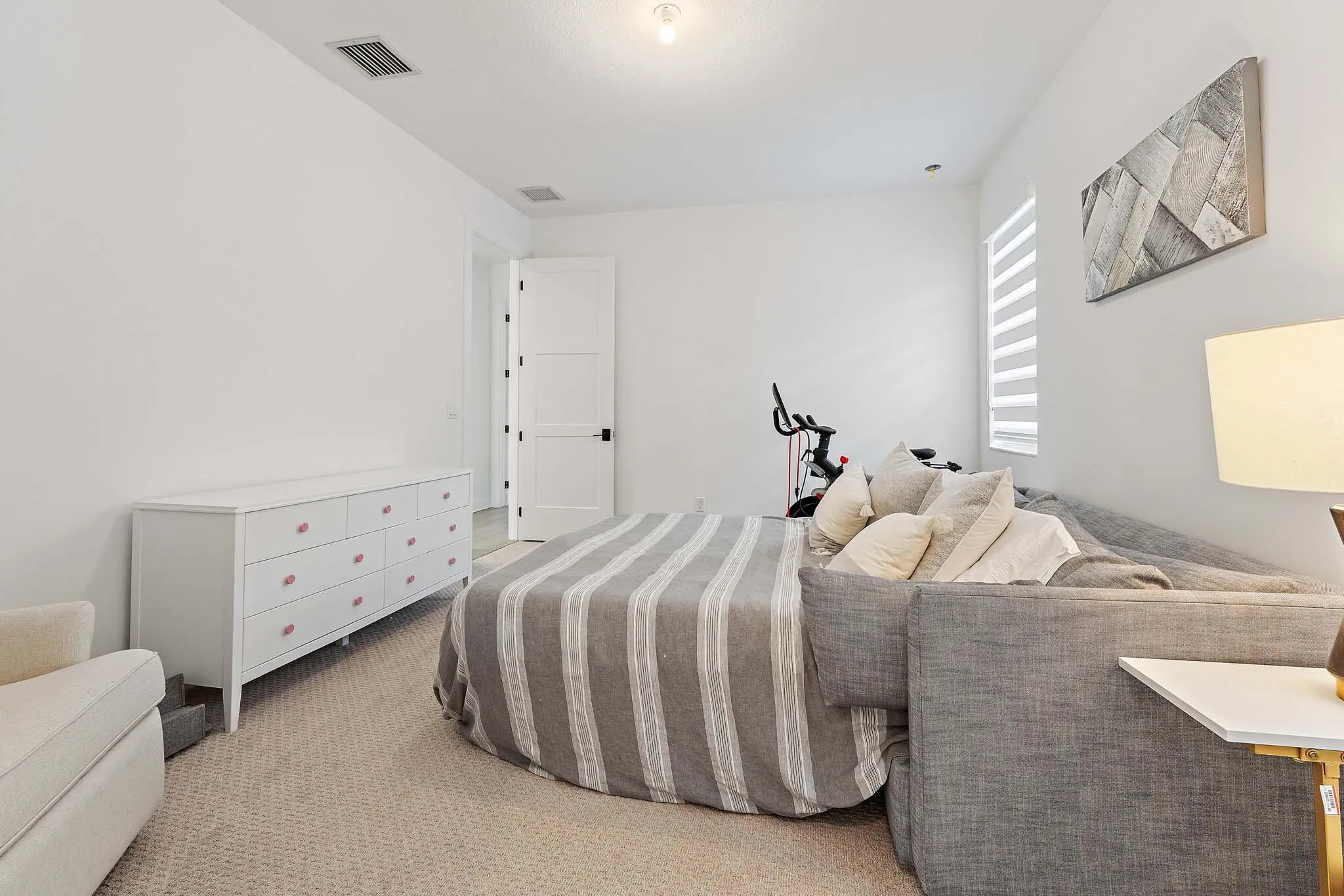 Bedroom with striped bedding, dresser, and sitting chair