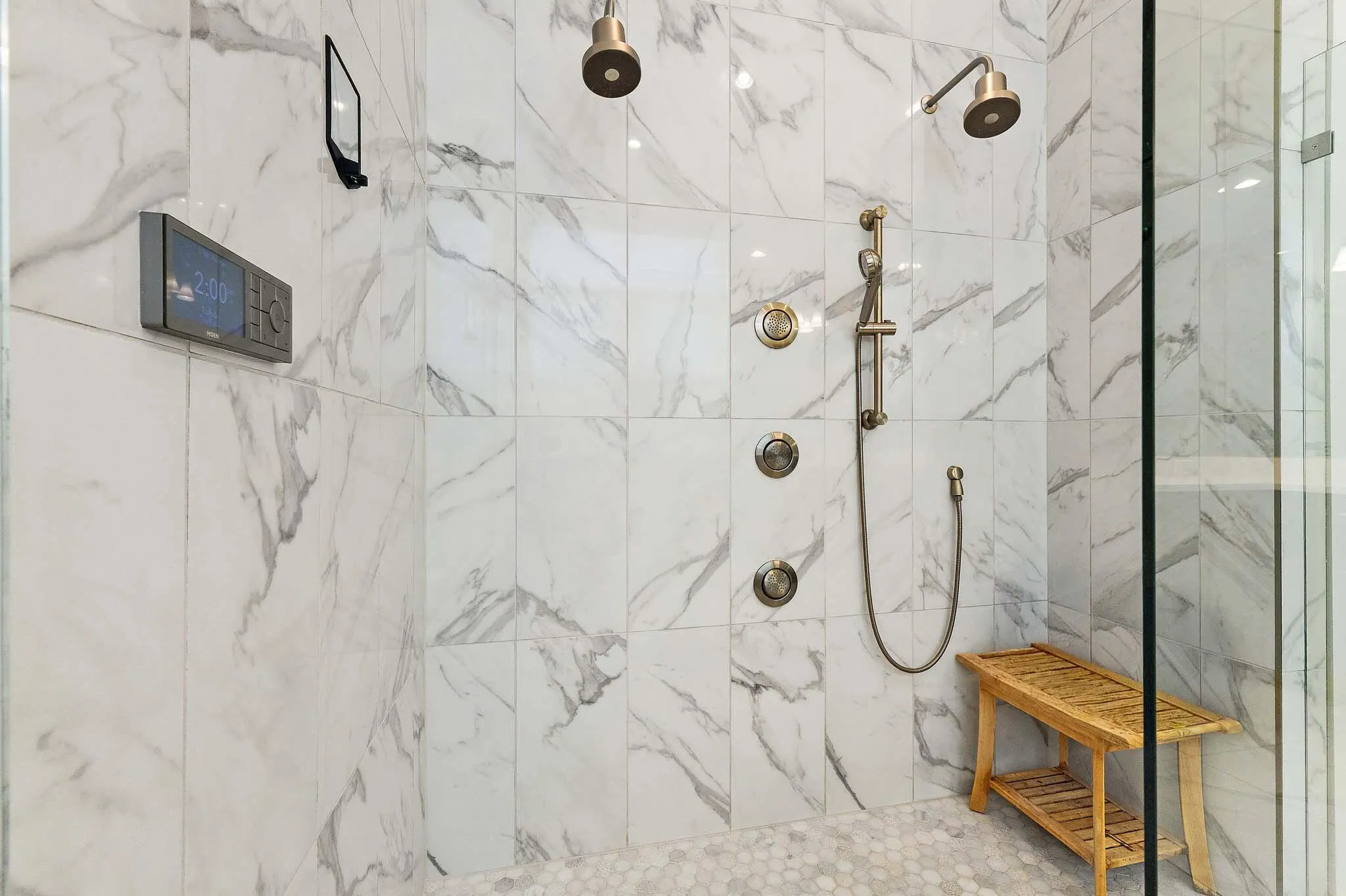 Marble shower with multiple showerheads and built-in bench