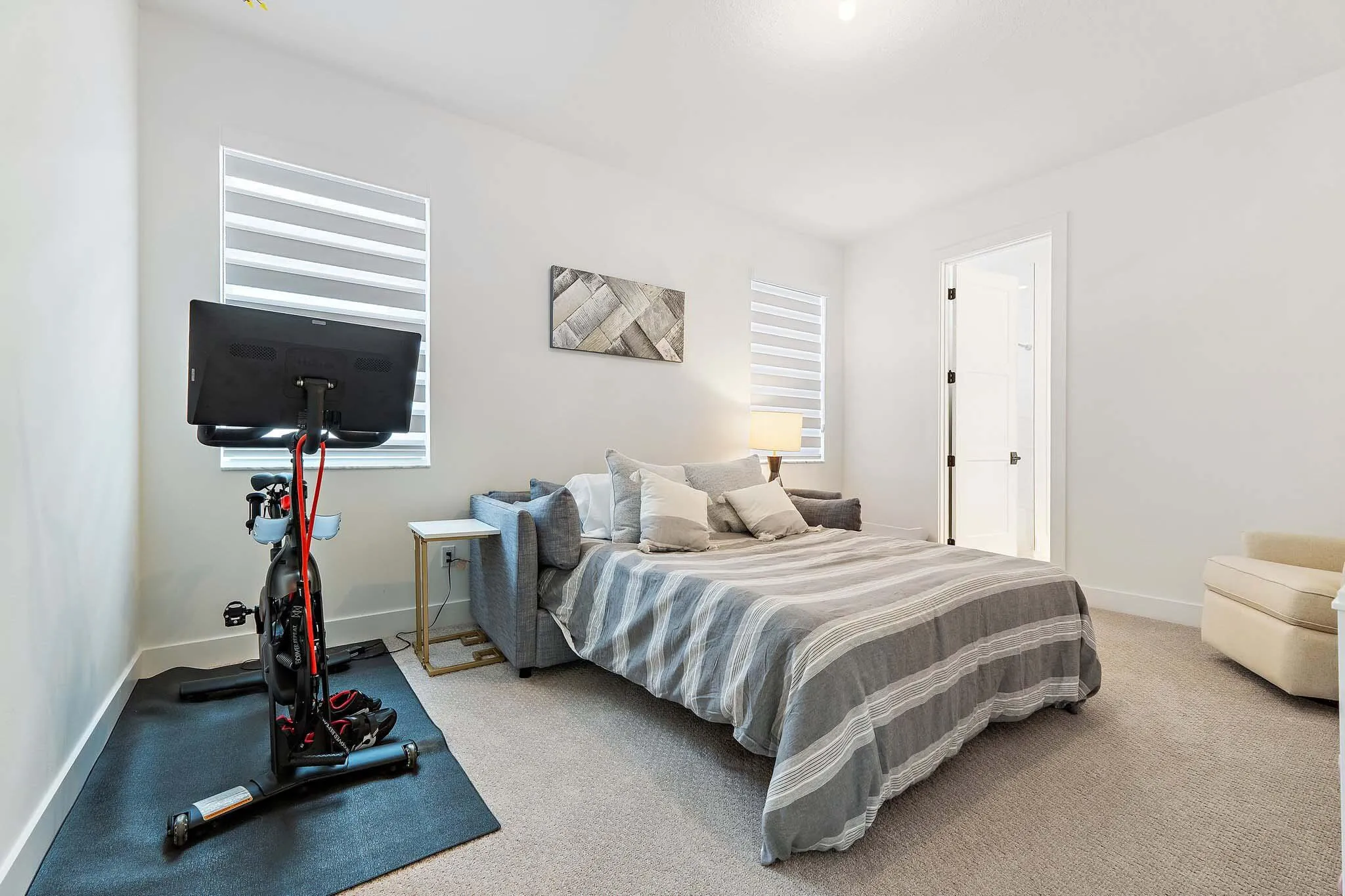 Bedroom with mounted TV, exercise bike, and carpet flooring